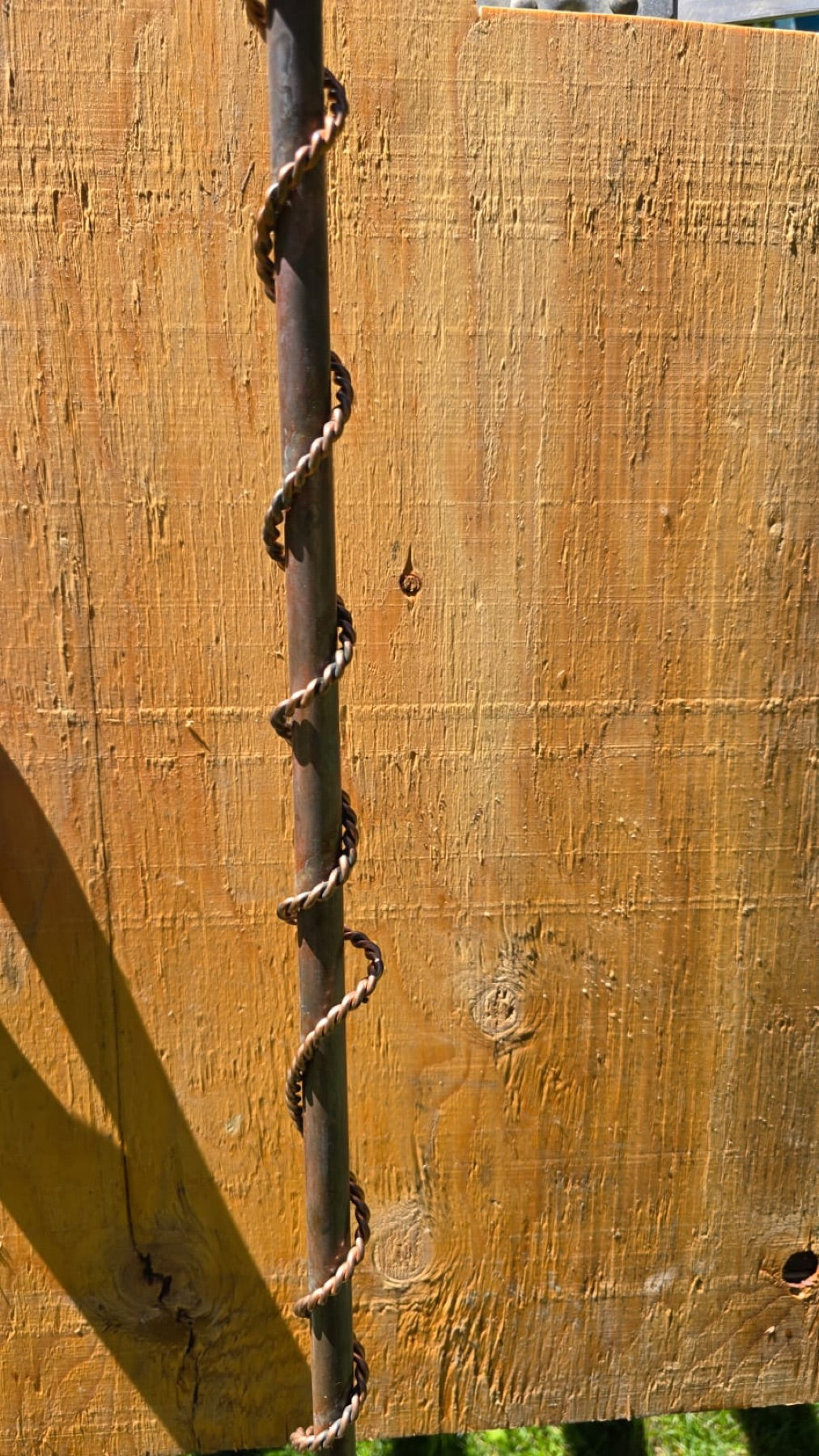 The twisted copper rod of the antenna against the workshop bench